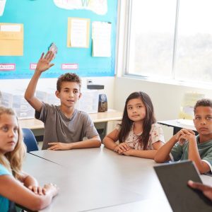 boy raising his hand in a classroom